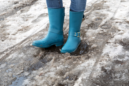 Standing in puddle in rubber boots, spring, melting snow.の写真素材