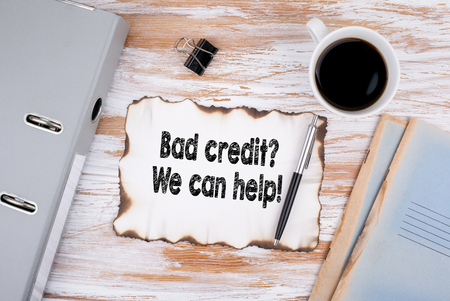 Bad credit, We can help. Business concept. Wooden desk with stationery and a cup of coffeeの写真素材