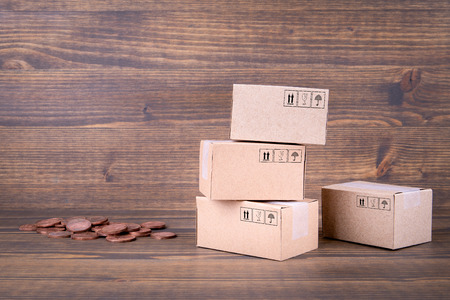Paper boxes and cash coins on wooden background. Selling goods or services online over the internetの写真素材