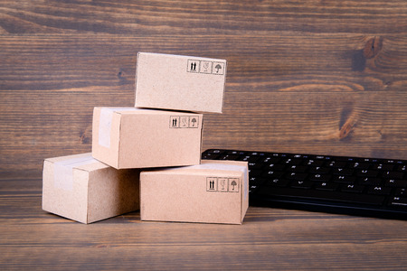 Paper boxes and computer keyboard on wooden background. Selling goods or services online over the...