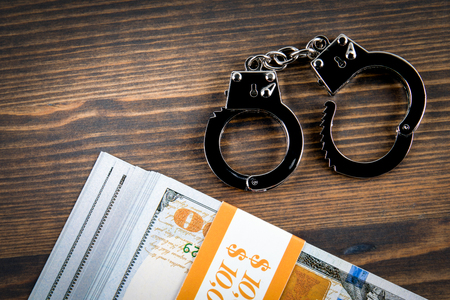 Handcuffs with money on a dark wood background. Corruption, crime and lawの写真素材