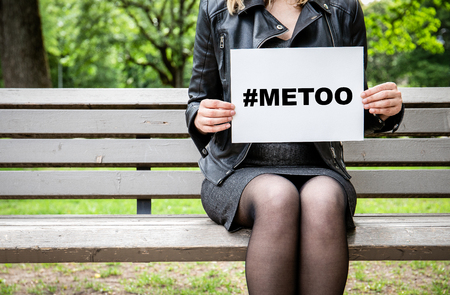 Hashtag for Mee Too movement Woman sitting on a bench at the park with a broadsheet againts sexual harassmentの写真素材