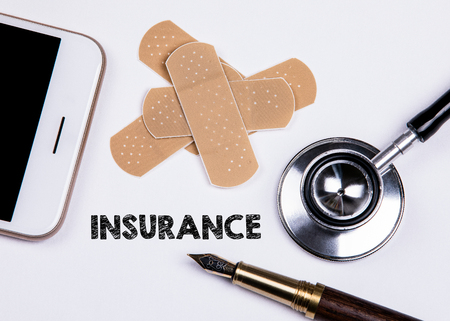 Insurance concept. Set of adhesive plasters, smartphone and stethoscope on white background. First aid and home helpの写真素材