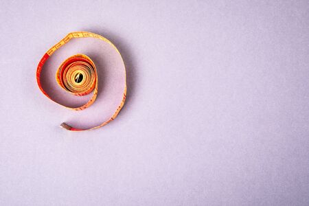 Measure tape on a gray background. Weight watching, healthy lifestyle and fitness concept. Space for text and pictureの写真素材