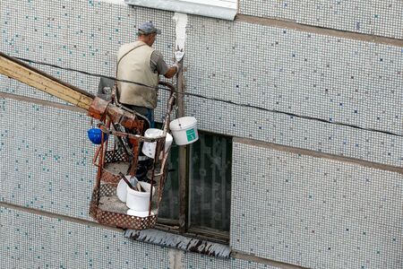 Riga, Latvia - August 19 ,2019 : Worker renovates block house facade.  Plastering sealing joint of external wall with puttyのeditorial素材