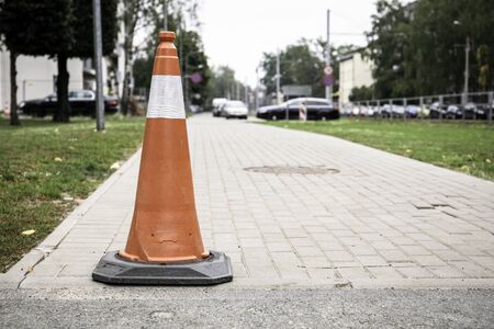 Plastic orange traffic cone on city street.の写真素材