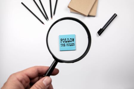 Follow the Rules. Learn, Law, Quality and Business concept. Magnifying glass in man's handの写真素材
