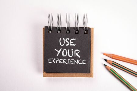 Use Your Experience. Education, work, skills and career ladders concept. Notebook with colored pencils on a white tableの写真素材
