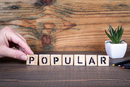 Popular. Social media, personality, branding and marketing concept. Wooden letters on the office...