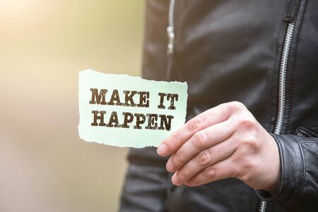 MAKE IT HAPPEN. Text on the sheet in handの写真素材