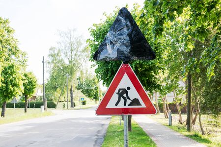 Roadworks signs on a street. Traffic regulation, rules, laws and procedures. Closed road sign with a plastic bagの写真素材