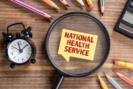 NATIONAL HEALTH SERVICE concept. Black magnifying glass, speech bubble and colored pencilsの写真素材