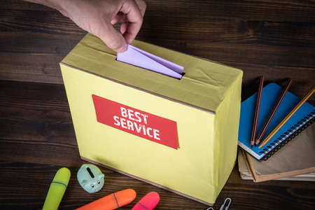 BEST SERVICE. Marketing, sales and feedbacks concept. Hand of a voter putting vote in the ballot boxの写真素材