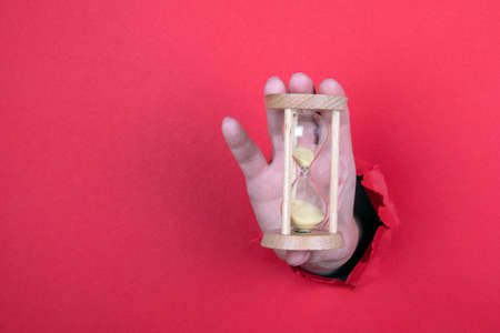 Hourglass in a woman s hand. Red backgroundの写真素材