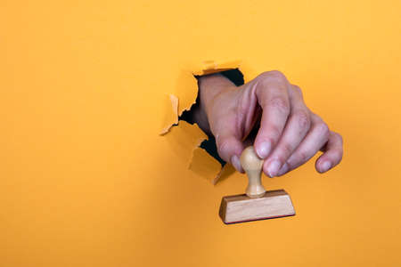 Wooden stamp in a womans hand. Approved, secret, restricted and confidential conceptの写真素材