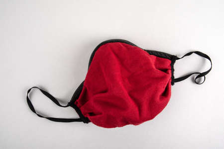 Red face mask on a gray background. Virus spread, regulations and public safety concept