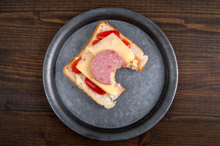 Bitten fresh sandwich on a metal plate. Dark wooden backgroundの写真素材