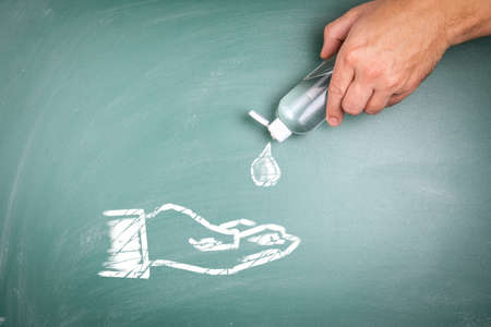 Hand disinfection. Plastic bottle in hand. Illustration on a green chalk boardの写真素材