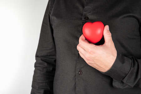 Heart diseases. Man holding red heart at chest. Health conceptの写真素材