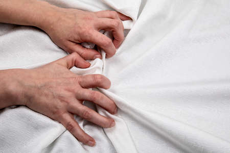 Two hands on a white cloth. Symbolizes stress, passion, love and sexual relationshipsの写真素材