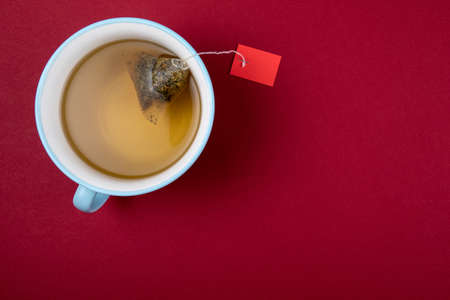 Blue mug with a tea bag. Red paper background. Top view, mockupの写真素材