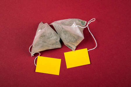 Teabags with yellow label. Top view, on a red background. Mockupの写真素材