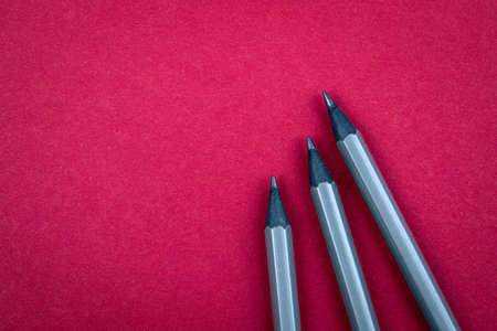 Grey pencils on a red background. Free text space for advertising and marketingの写真素材