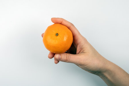 One tangerine in a womans hand on a white backgroundの写真素材