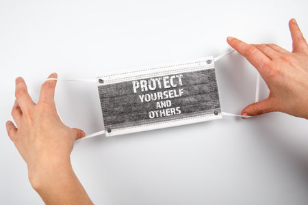 Protect yourself and others. Face mask in a womans handsの写真素材