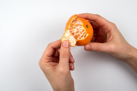 Woman peeling a tangerine. Hands on a white background. Vitamin c, fruit, health and nutrition conceptの写真素材