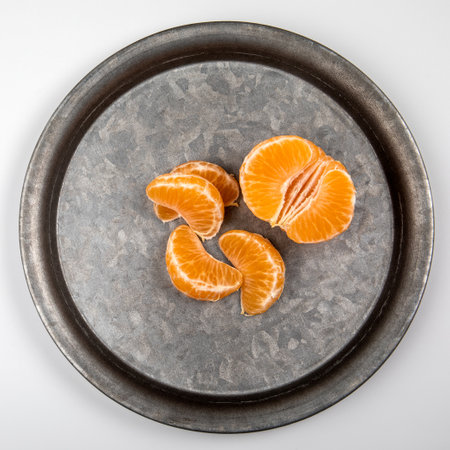 Peeled tangerine fruit, Mandarin pieces on a metal plateの写真素材