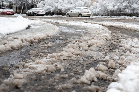 Road clening from snow and salt sprinkling . Melted snow on the roadの写真素材