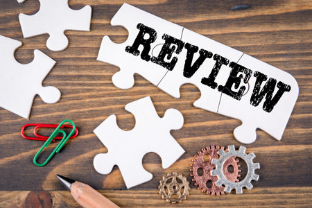 REVIEW. Business concept. White puzzle pieces on a wooden tableの写真素材