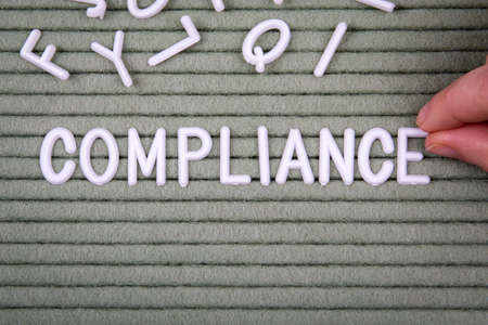 Compliance. Business concept. White letters of the alphabet with a womans hand