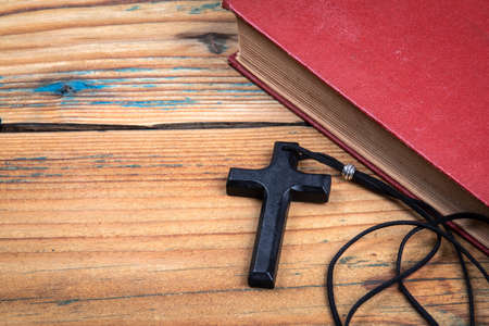 Wooden Cross with with leather cord and Bible on the table