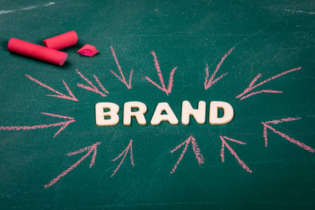 BRAND. White wooden alphabet letters on a green chalk board. Red arrowsの写真素材