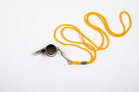 Metal whistle with a yellow cord on a white backgroundの写真素材
