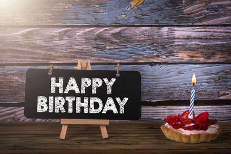 Happy Birthday. Fruit cake with one anniversary candle on a wooden backgroundの写真素材