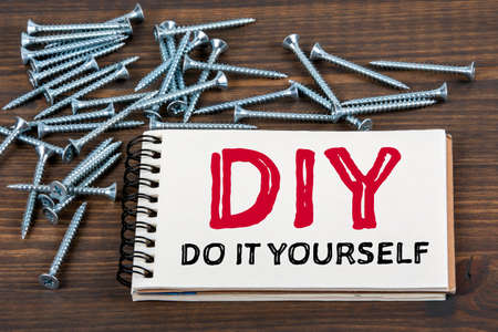 DIY do it yourself. Notebook and screw on a wooden tableの写真素材