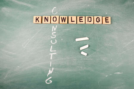 Knowledge and Consulting. Wooden alphabet letters on a green chalk boardの写真素材