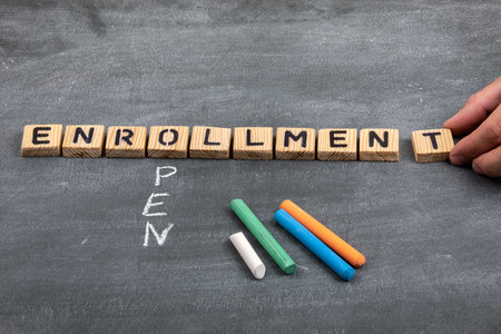 Open enrollment concept. Letters of the alphabet and colored pieces of chalk on a black chalkboardの写真素材