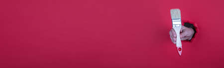 Painters brush in a womans hand on a Red horizontal bannerの写真素材