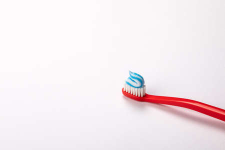 Toothpaste on a red toothbrush. White background with space for text and informationの写真素材