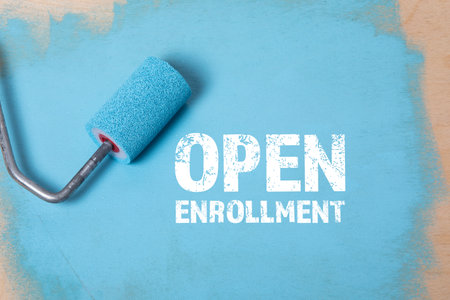Open Enrollment. Paint roller with blue paint on a wooden surfaceの写真素材