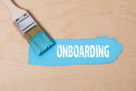 ONBOARDING. Paint brush with blue paint on a wooden surfaceの写真素材