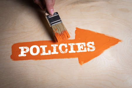 Policies concept. Orange painted arrow on a wooden surfaceの写真素材