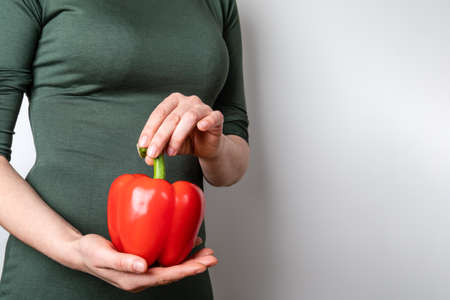 Woman in a green dress with red paprika in hand on a white backgroundの写真素材
