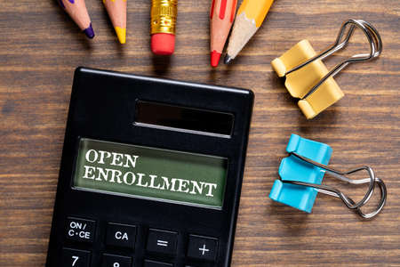 Open Enrollment. Calculator and office supplies on a wooden tableの写真素材
