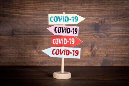 COVID-19. Directional arrows on a wooden background