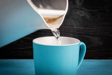 Pour a cup of hot water from electric kettle. Iron and calcareous water